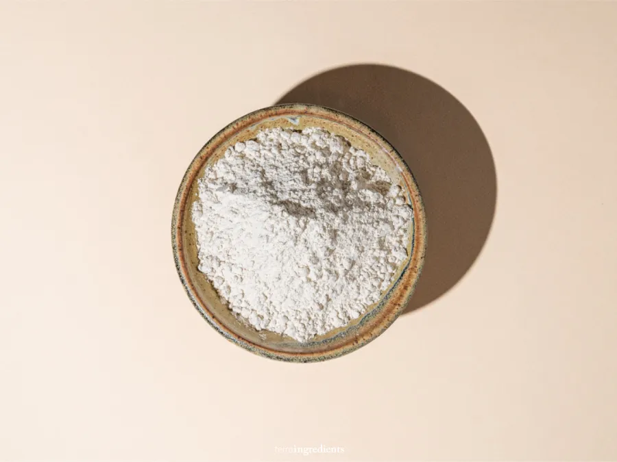 A bowl of fonio flour sits on a beige background.