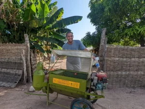 Malick Diedhiou of Terra Ingredients stands behind a fonio thresher in Senegal.