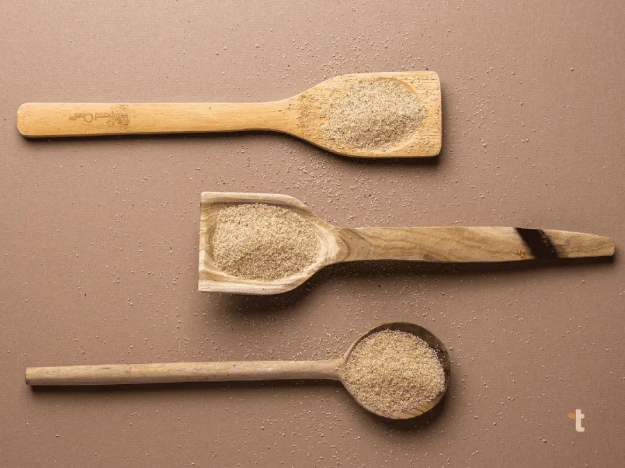 Pearled fonio grain is displayed on 3 different wooden spoon variations