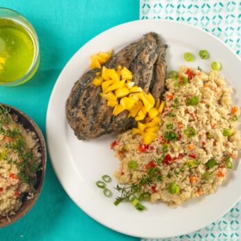 Caribbean Fonio with Jerked Chicken and Mango displayed on a blue table.