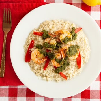 Lemony Fonio with Seared Shrimp and Pesto displayed on a red plaid cloth