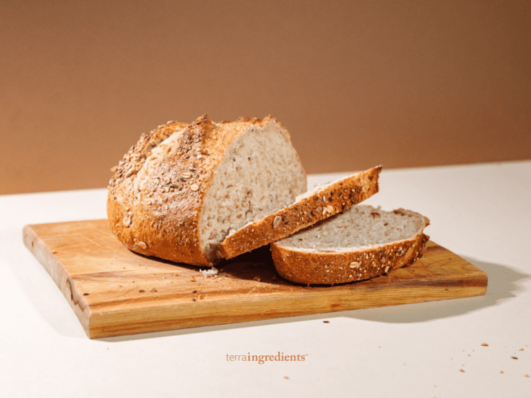 A loaf of fonio bread is sliced open on a cutting board