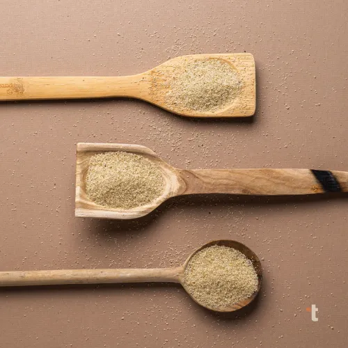 Pearled fonio grain is displayed on 3 different wooden spoon variations