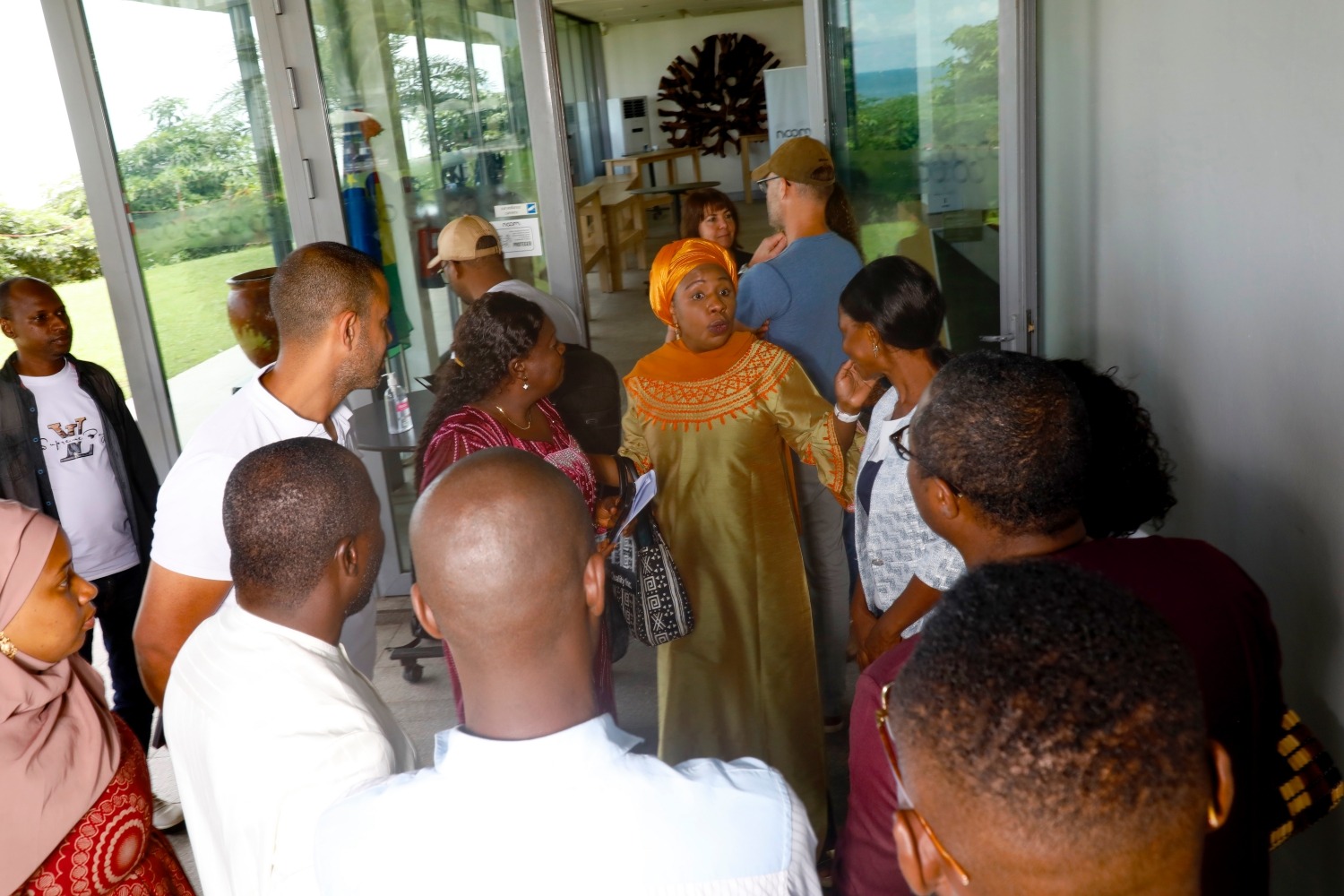 A woman speaks to a small group outside of a building.