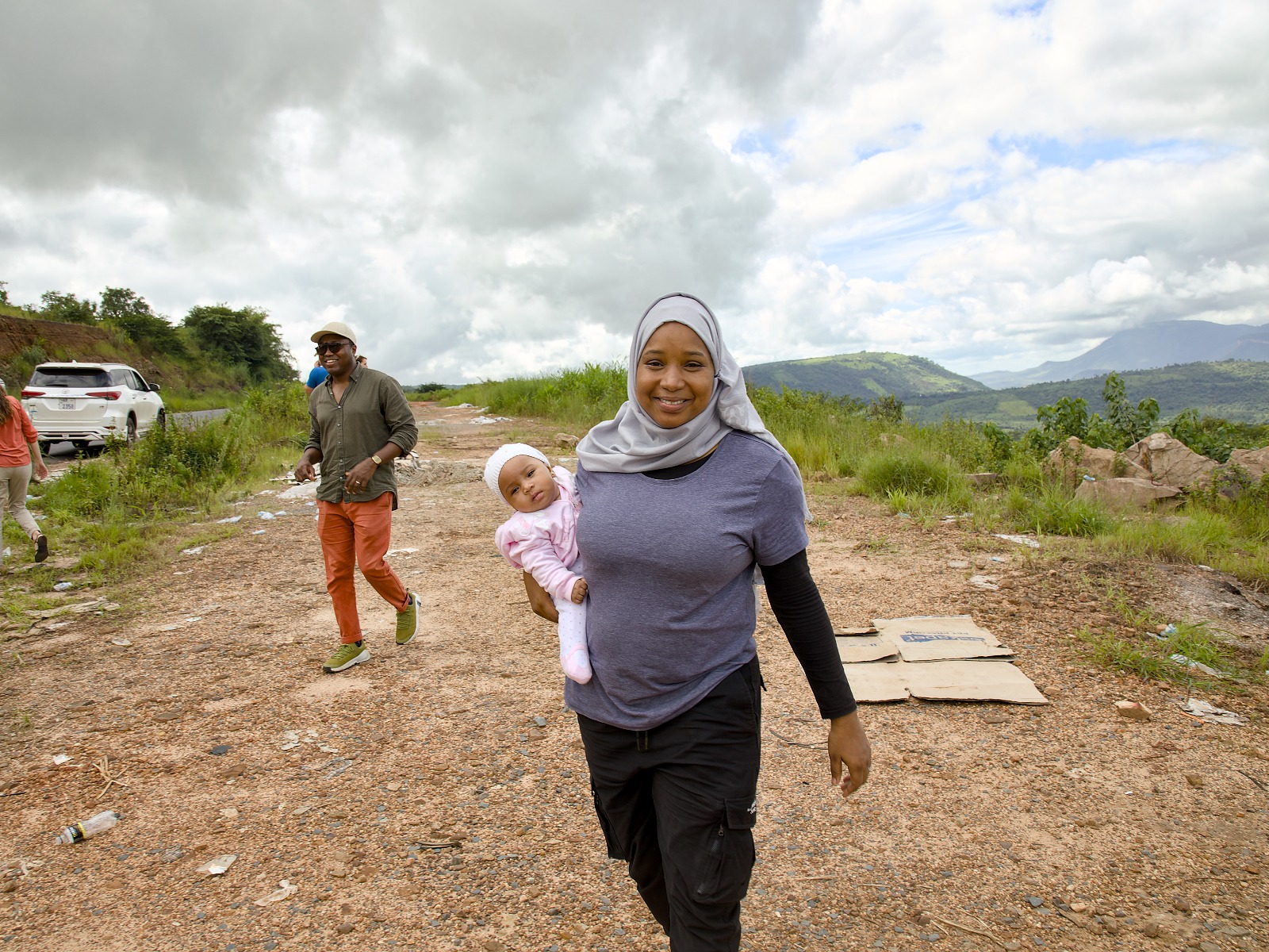 A woman is carrying her baby daughter along a dirt road in Guinea