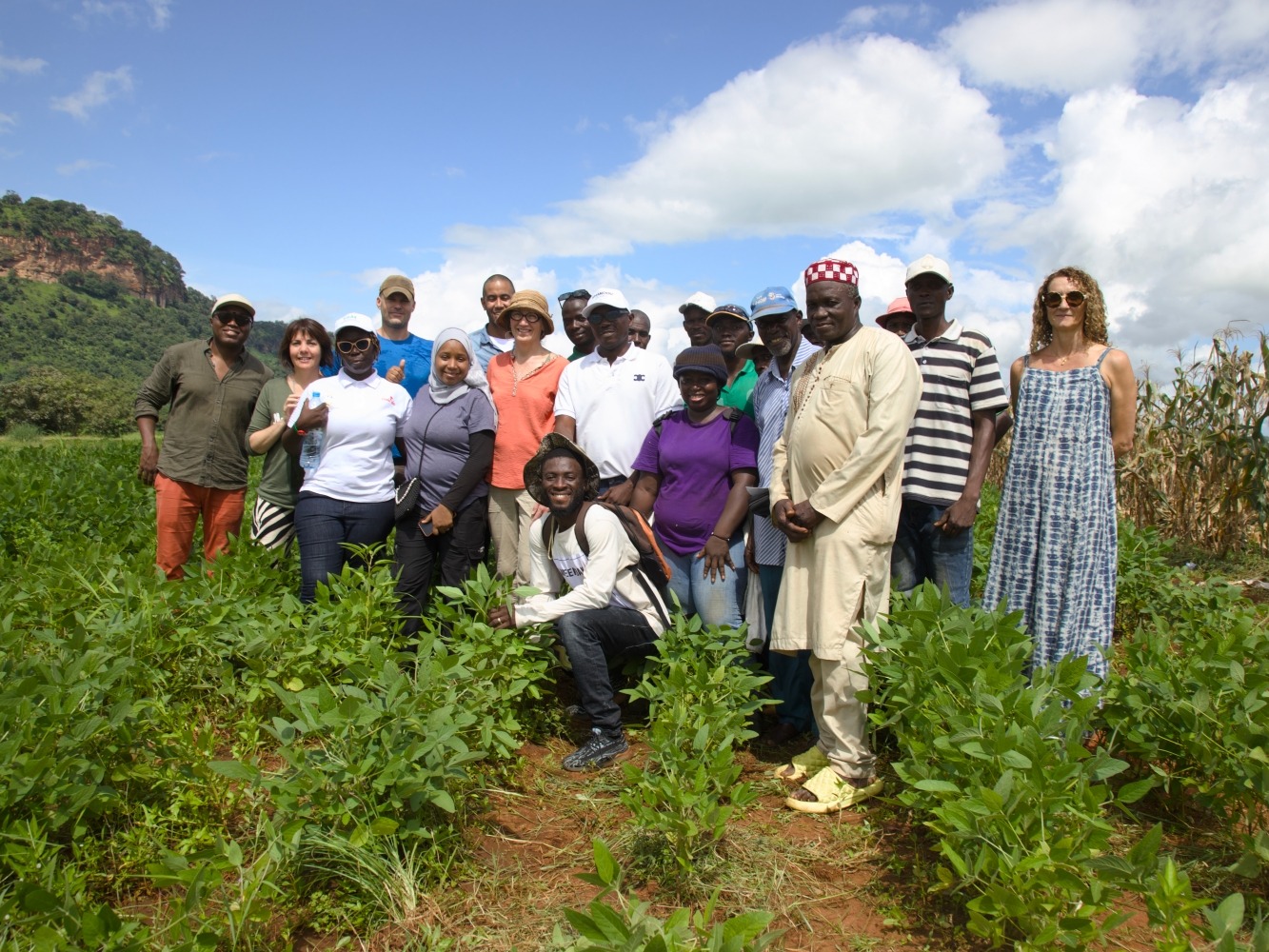 A group of farmers pose for a photo in a field of crops.