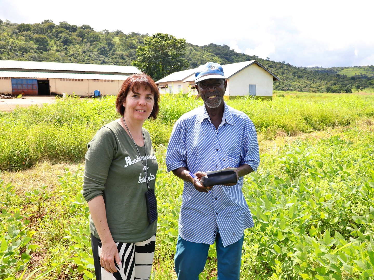 A woman and a man pose for a photo together while standing in a field of green crops
