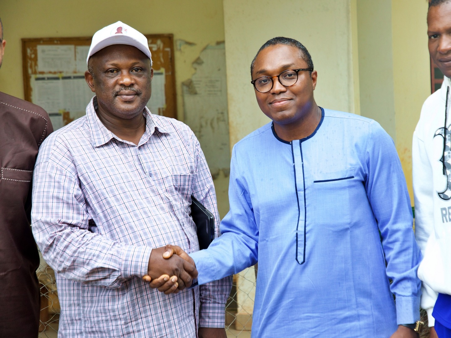 Two men shake hands while posing for a photo