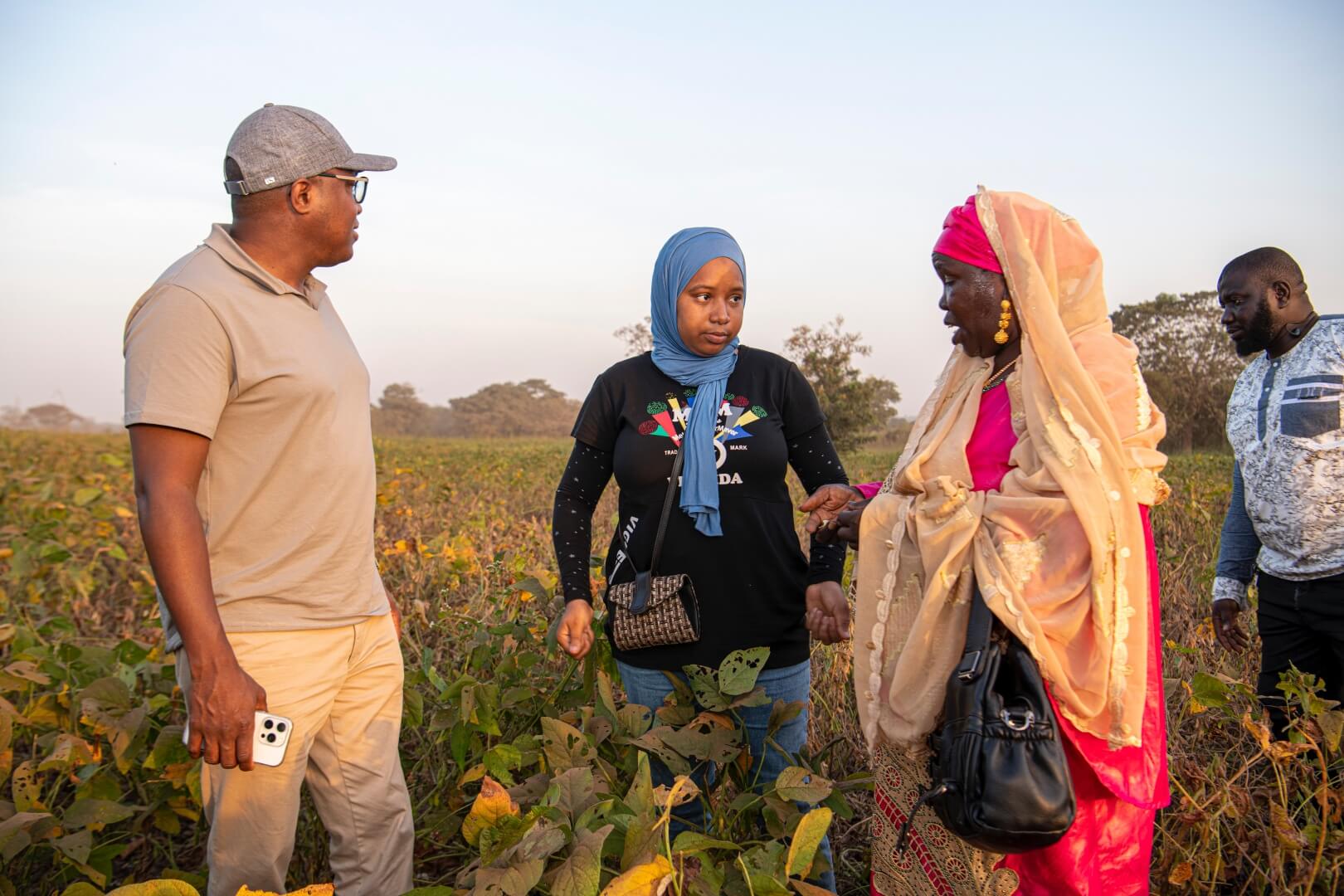 A man and two women stand in the middle of a field of tall grass to have a conversation